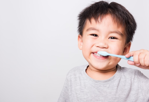 クローズアップアジアの顔、小さな子供男の子の手は彼が自分で歯を磨く歯ブラシを保持しています。
