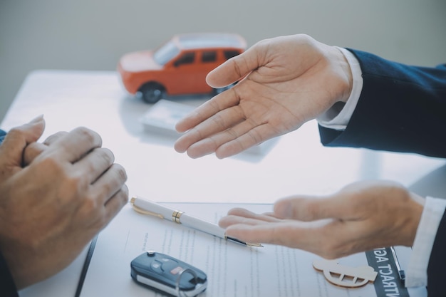写真 クローズアップ アジア人男性 車のセールスマンやセールスマネージャーが 車を売ることを提案し 車の契約と保険に署名する条件を説明し 読み上げます