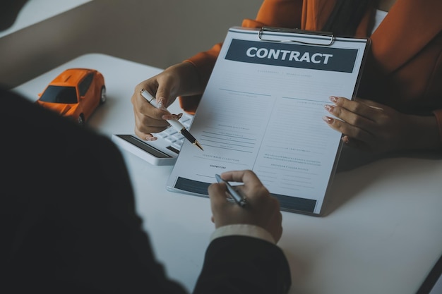 Photo closeup asian male people car salesman or sales manager offers to sell a car and explains and reads the terms of signing a car contract and insurance