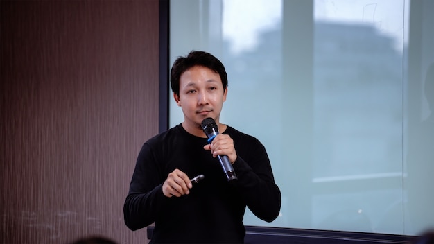 Closeup Asian Speaker or lecture with casual suit on the stage in front of the room presen