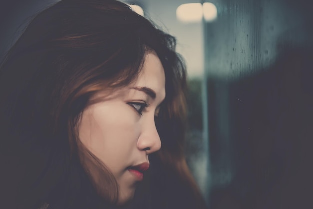 Photo closeup asian woman sad from love at mirror with reflection in a raining day vintage styleheartbreak woman conceptstress girl