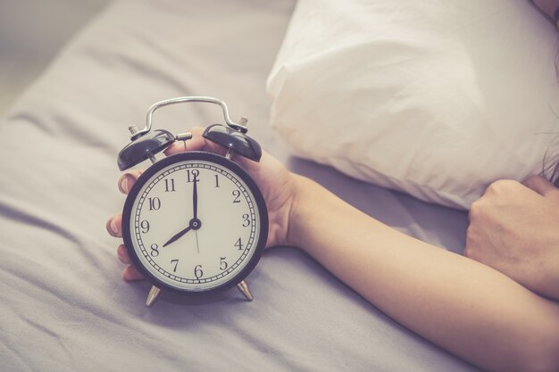 Closeup asian woman turn off alarm clock in good morning