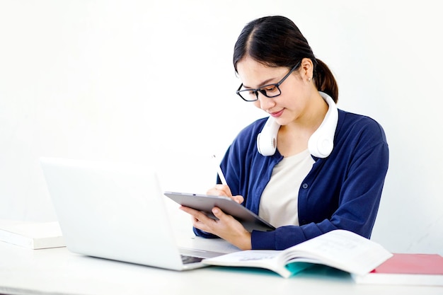 Closeup Asian young female student in casual cloth make a short note on tablet for the exam