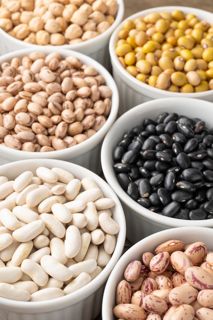 Closeup of assorted beans on white bowls.