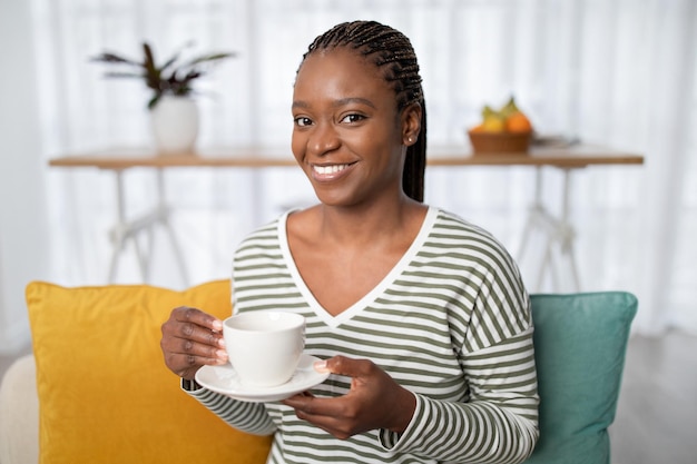 Closeup of attractive african lady drinking herbal tea at home