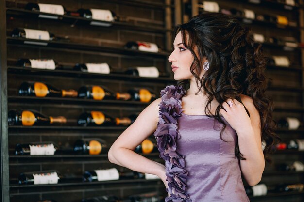 Closeup of attractive young woman standing in front of wine and champagne bottles