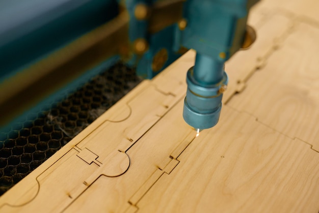 Closeup automated CNC laser machine operating with wooden plank. Woodworking, cutting and engraving process