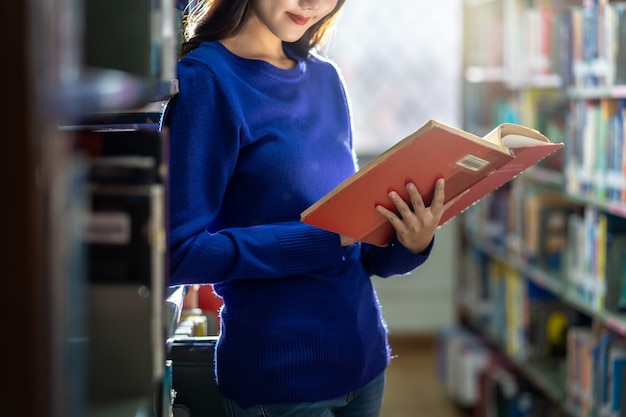 Closeup Aziatische jonge student in casual pak staande en hand met het boek en lezen