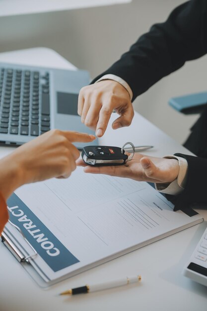 Closeup Aziatische mannelijke mensen autoverkoper of verkoopmanager biedt aan een auto te verkopen en legt uit en leest de voorwaarden voor het ondertekenen van een auto-contract en verzekering