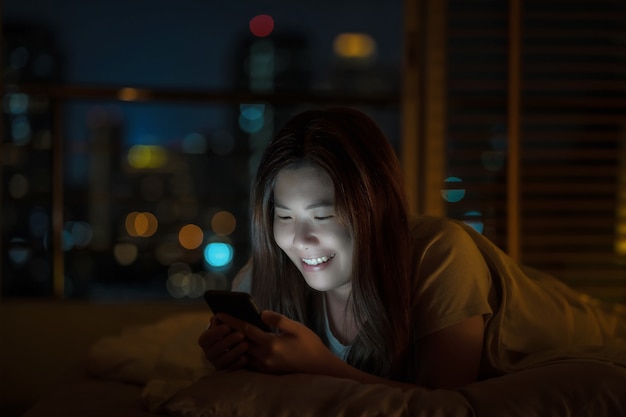 Closeup aziatische vrouw slapen en het gebruik van slimme mobiele telefoon voor sociaal netwerk of videoconferentie