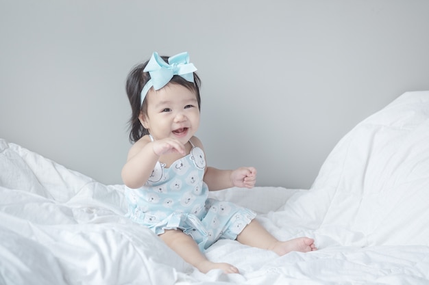 Closeup baby girl sit on bed in funny motion