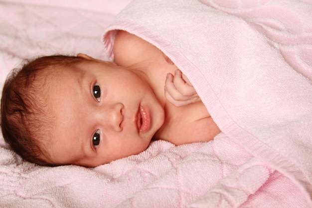 ピンクのタオルに横たわっている赤ちゃんのクローズアップ