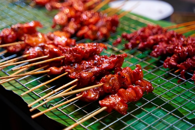 A closeup of a barbecued chicken fillet on a wooden stick Asian sate