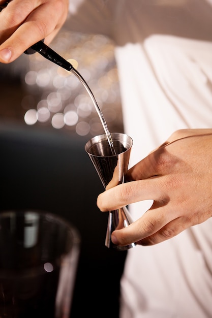 Closeup of bartender hands pouring alcoholic drink.Professional drink making