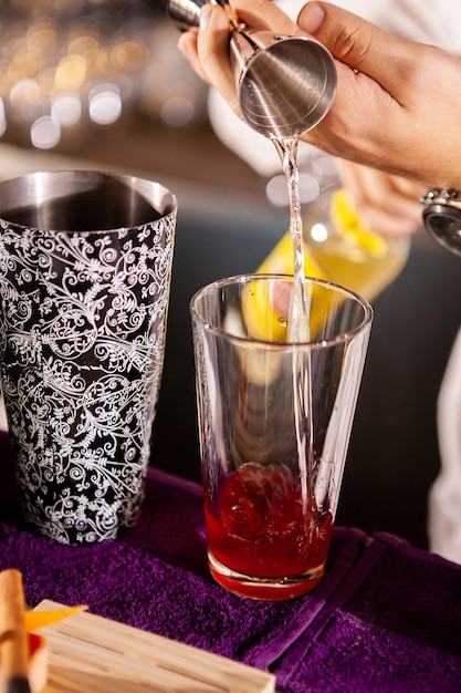 Крупным планом руки бармена наливают алкогольный напиток. Изготовление профессиональных напитков