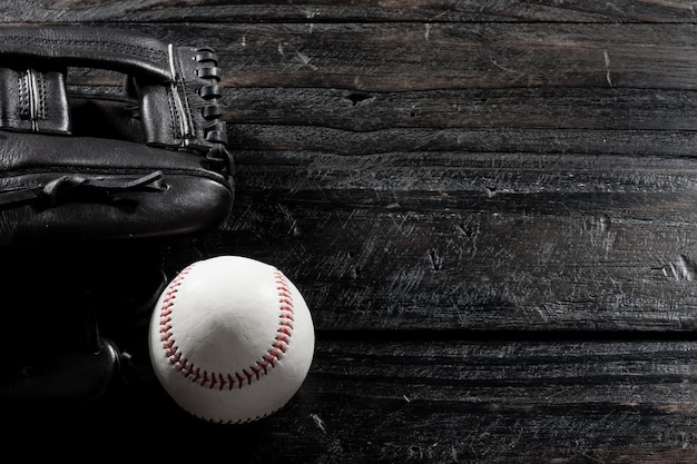 Closeup baseball glove and baseball on wood board dark theme sport concept