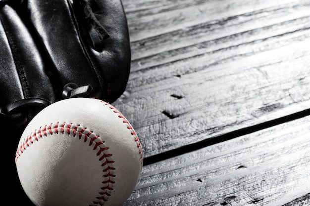 Photo closeup baseball glove and baseball on wood board dark theme sport concept