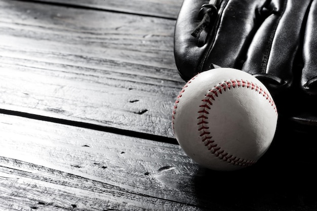 Closeup baseball glove and baseball on wood board dark theme sport concept