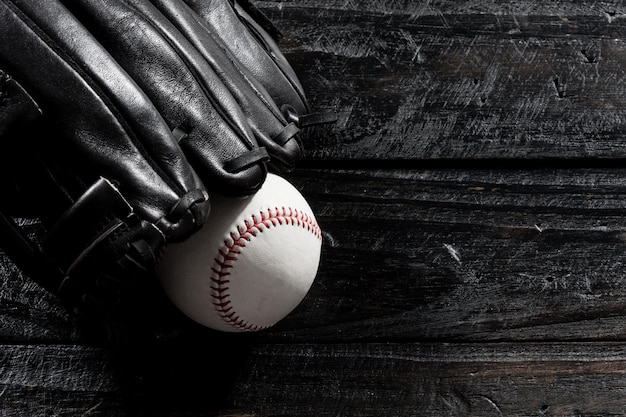 Closeup baseball glove and baseball on wood board dark theme sport concept