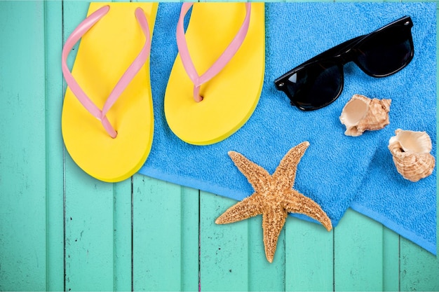 Closeup of beach accessories on floor Flipflops sunglasses sea starstowel