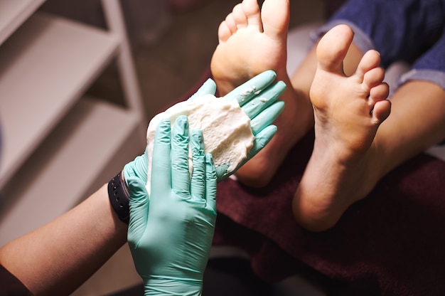 Photo closeup of beautician's hands and feet of woman having a pedicure in a beauty spa. body care concept