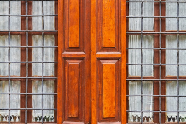 Closeup of a beautiful black forged fence on a window with shutters in a old house