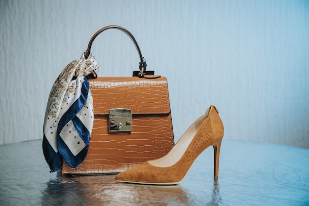 Photo closeup of a beautiful brown leather handbag next to a suede shoe