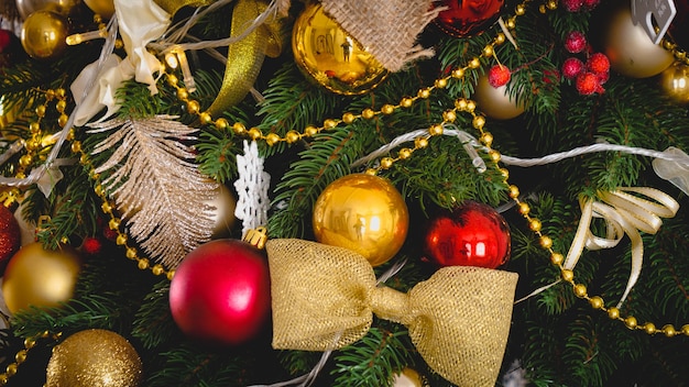 Closeup of beautiful decorations and garlands on Christmas tree in living room at house. Winter holidays background or backdrop.