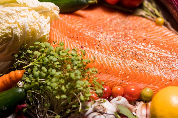 Closeup beautiful fresh salmon fillet with seasonings, herbs and vegetables on the table. Food, restaurant, Haute cuisine concept