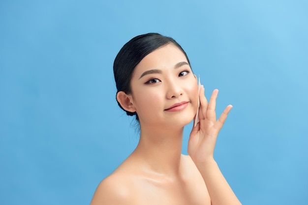 스튜디오에서 오일 흡수 시트 미용 제품을 사용하여 자연스러운 화장을 한 아름다운 행복한 아시아 소녀 모델의 근접 촬영