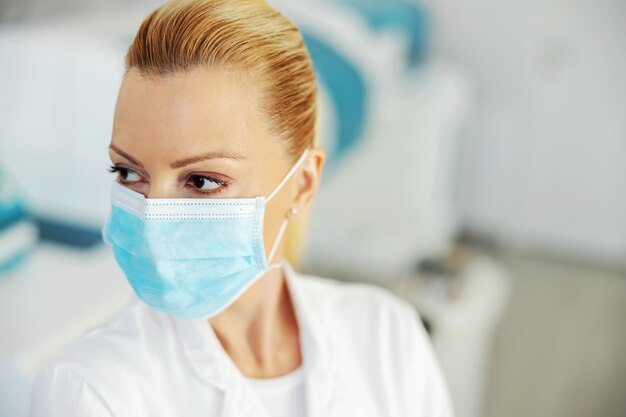 Closeup of beautiful lab assistant with protective sterile face mask on. Covid 19 outbreak concept.