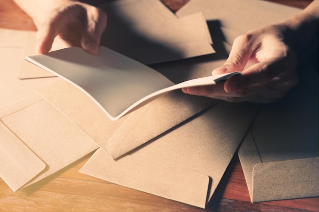 closeup of beautiful man hands opening blank white book on the brown wooden tabel background