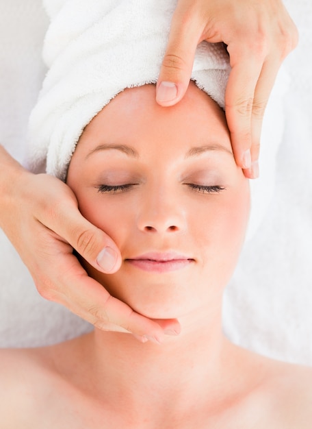 Closeup of a beautiful red-haired woman receiving a massage in a spa centre