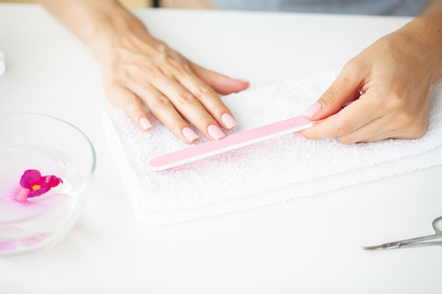 Closeup of beautiful woman hands getting manicure at home.