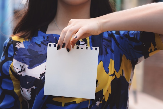 Closeup of a beautiful woman showing a blank notepad.