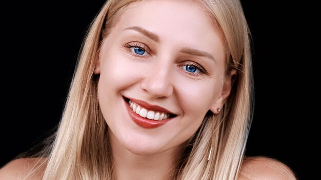 Closeup of beautiful womans face young blueeyed smiling blonde girl looking at camera antiaging care