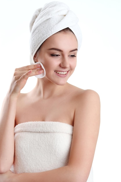 Крупный план красивой молодой женщины с банным полотенцем на голове, закрывающей грудь на белом