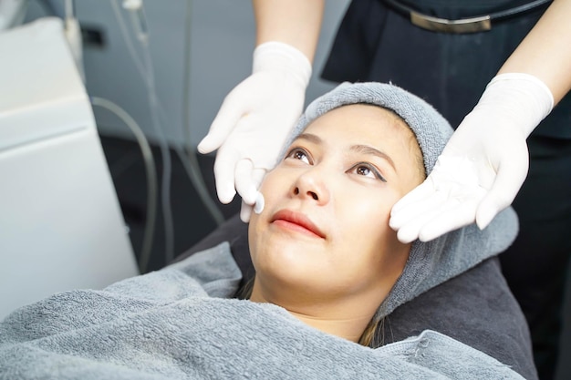 Primo piano spettacolo di infermiera di bellezza di crema scrub viso sulle mani prima di fare un massaggio facciale sul viso del cliente