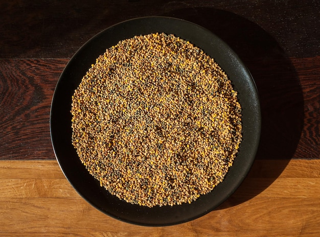 Closeup of bee pollen on black plate organic medicinal food top view on wooden table