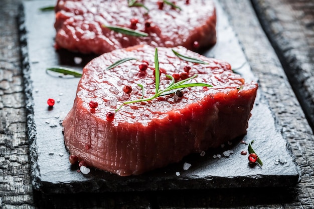 검은 바위에 로즈마리와 후추를 곁들인 쇠고기의 근접 촬영