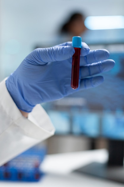 Closeup of biologist researcher man holding medical vacutainer with blood sample