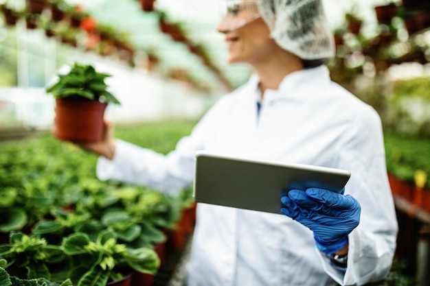 Closeup of biologist using digital tablet while working in a greenhouse