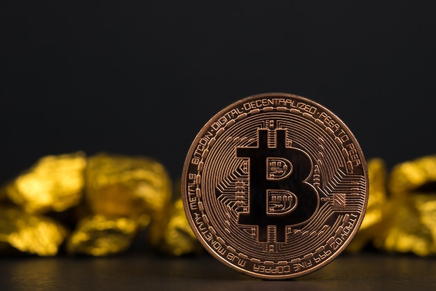 Closeup of bitcoin digital currency and gold nugget on black background,