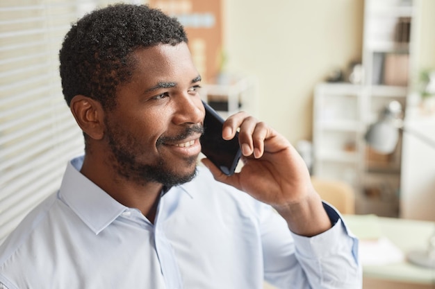 Closeup black businessman calling by phone in office and smiling