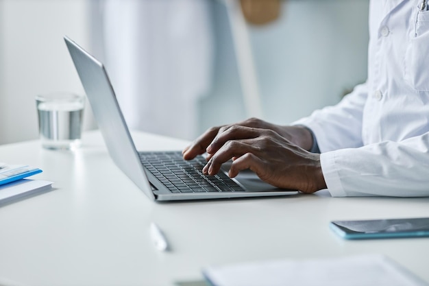 Closeup black doctor using laptop in office