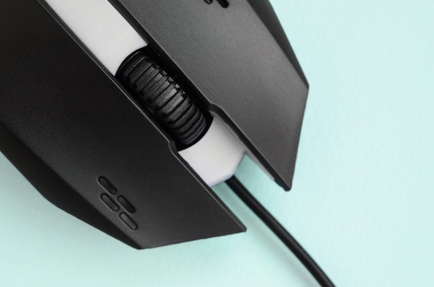 Closeup of a black gaming optical mouse on a blue background