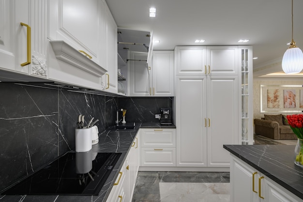 Primo piano al piano di lavoro in granito nero della cucina domestica bianca con pavimento in marmo