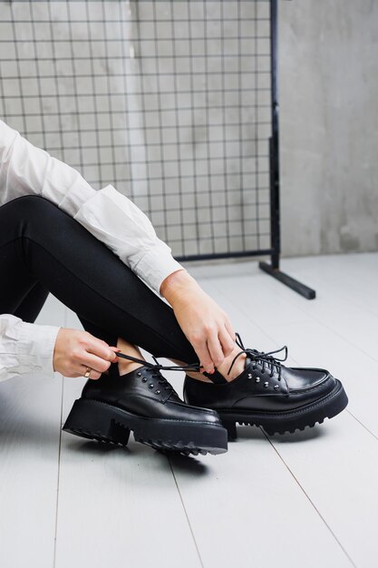 Крупный план черных кожаных туфель на шнуровке на женских ногах в черных леггинсах Женская стильная осенняя обувь