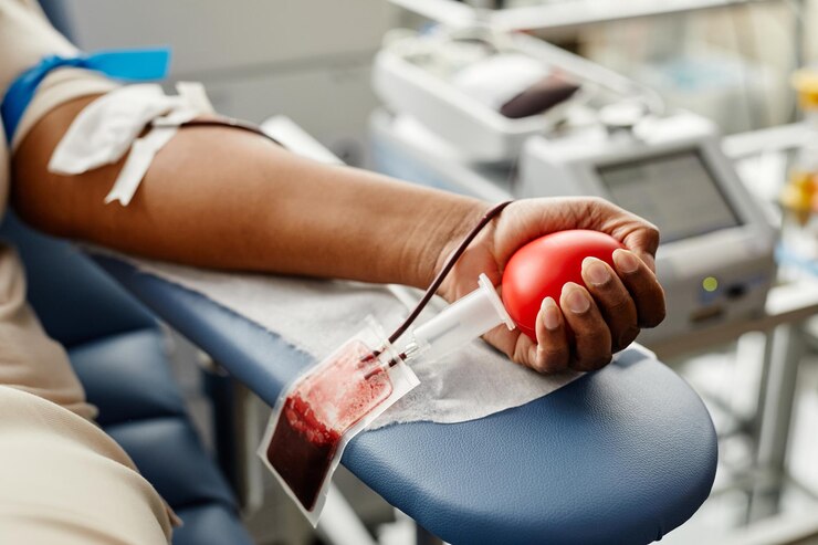 Closeup of black woman donating blood focus on hand holding red ball with tubing copy space