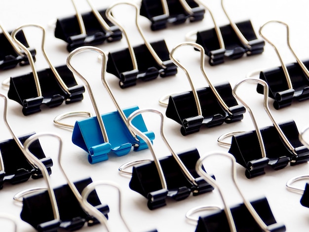 Closeup blue paper clip among black paper clips